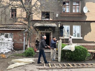 Public utility employees repairing the windows in a building that was damaged by shelling. Slavyansk, April 22, 2022