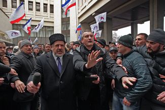 Рефат Чубаров и Сергей Аксенов (слева направо на первом плане) пытаются предотвратить столкновения участников митинга у здания Верховного совета Крыма. Симферополь, 26 февраля 2014 года