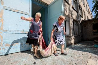 Женщины убирают здание школы после обстрела