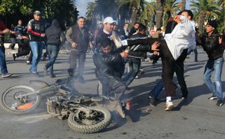 14 января 2011 года. Протестующие избивают полицейского в столице Туниса в день отставки президента Бен Али