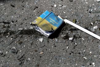 Учебник по английскому языку на улице у попавшей под обстрел школы в жилом районе Харькова