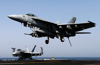 Американские истребители F/A-18E возвращаются на авианосец после нанесения авиаударов по территориям «Исламского государства» в Ираке. 12 августа 2014 года