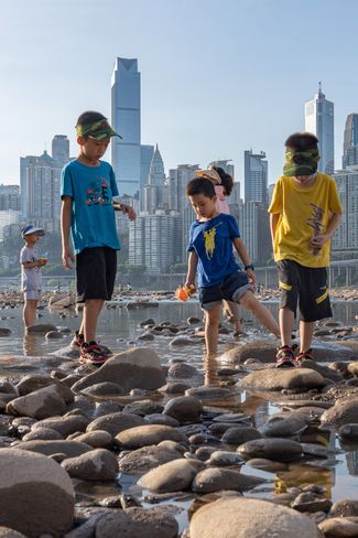 Дети ловят крабов в русле реки Цзялинцзян в Чунцине. 21 августа 2022 года