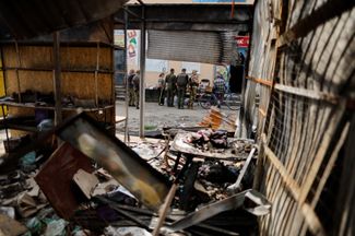 Украинские военные и мирные жители стоят перед импровизированным прилавком магазина в Бахмуте