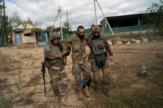 Раненый украинский солдат в сопровождении товарищей идет за медицинской помощью в только что освобожденном селе Щурово Донецкой области