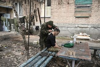 A Ukrainian soldier cuts his colleague's hair in the yard of a house in Bakhmut