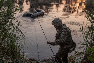 Украинский военный переправляется через реку недалеко от города. 19 июня 2022 года