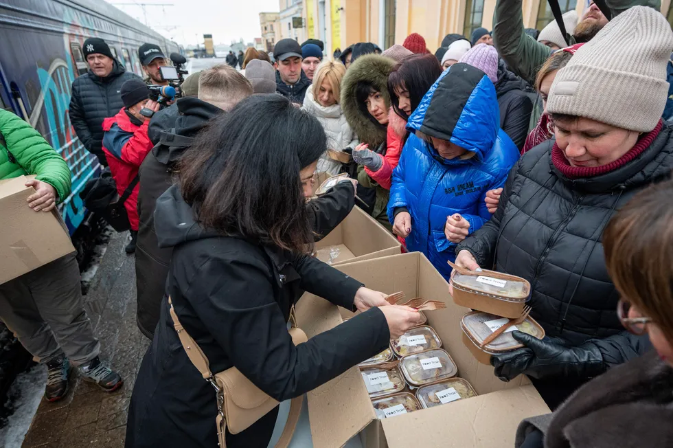 Работники поезда-кухни передают еду людям на железнодорожном вокзале Харькова