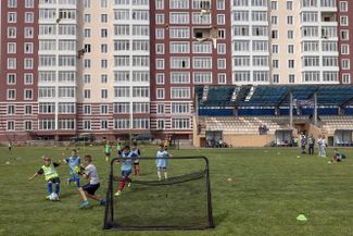 Детские футбольные команды из Ирпеня и Гостомеля играют первый после начала войны в Украине матч перед жилой многоэтажкой в Гостомеле. 23 июня 2022 года