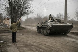 A local resident welcomes a Ukrainian infantry fighting vehicle that is moving to the front line in the Bakhmut area