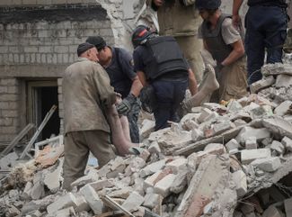 Спасатели достают из-под завалов разрушенной части дома тела жильцов