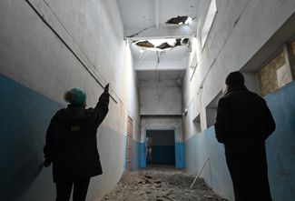 Жительница поселка Степановка показывает поврежденную осколками снаряда крышу местной школы. Степановка расположена в девяти километрах к северо-западу от Херсона