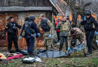 Полицейские осматривают тела погибших, найденные среди завалов, которые остались от разрушенного российской ракетой дома