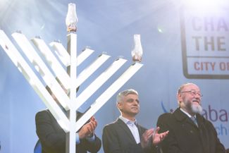 Мэр Лондона Садик Хан и главный лондонский раввин Эфраим Мирвис (крайний справа) на церемонии зажигания меноры на Трафальгарской площади в честь начала еврейского праздника Ханука. 22 декабря 2019 года