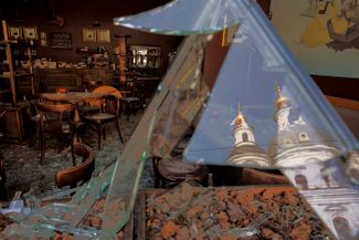 Отражение Успенского собора в разбитых окнах кафе в центре Харькова, пострадавшего при обстреле
