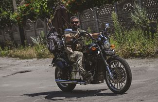 Украинский военный едет на мотоцикле по пустым улицам города