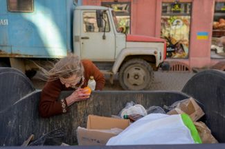 Женщина ищет еду в мусорном баке в центре Одессы