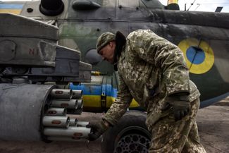 Украинский техник заряжает неуправляемые ракеты в блок вертолета Ми-8 на одном из аэродромов страны
