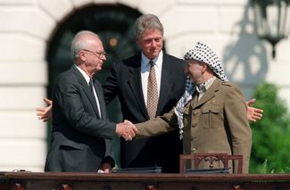 Ицхак Рабин и Ясир Арафат пожимают друг другу руки после подписания соглашений в Осло. Между ними — президент США Билл Клинтон. Вашингтон, 13 сентября 1993