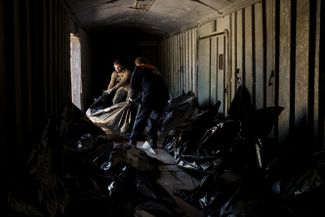 Украинский военнослужащий и работник железной дороги грузят в рефрижераторный вагон тела российских солдат, погибших под Харьковом.