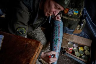 Командир артиллерийского расчета, 45-летний Александр, наносит имена погибших товарищей на снаряд перед запуском.