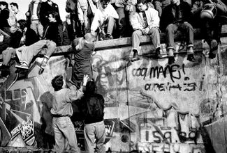 Жители Западного Берлина забираются на стену. 10 ноября 1989 года