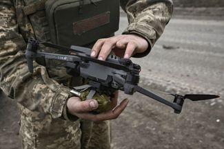 Украинский военный прикрепляет ручную гранату к беспилотнику