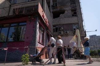 Жители Киева возле одного из зданий, поврежденных обломками российских дронов