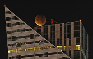 Луна проходит над небоскребом в Варшаве