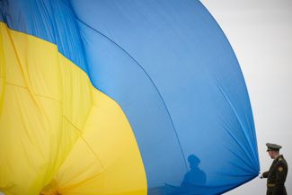 Почетный караул поднимает флаг Украины во время церемонии, посвященной первой годовщине освобождения Бучи