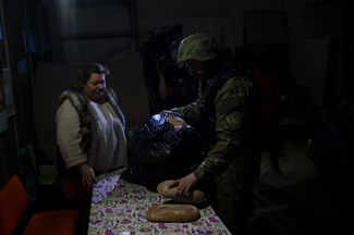 Полицейский спецназа раздает гуманитарную помощь жителям, которые прячутся в подвалах