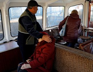 Мужчина успокаивает пожилую женщину в пароме, на котором оккупационные власти вывозят жителей Херсона на левый берег Днепра — ближе к границе с оккупированным Крымом