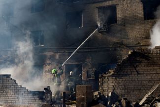 Firefighters extinguish a fire at the site of a Russian strike in Brovary, March 14, 2026