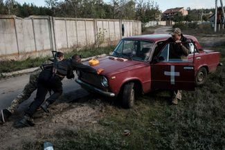 Солдаты толкают гражданскую машину, чтобы ее можно было отбуксировать в другое место