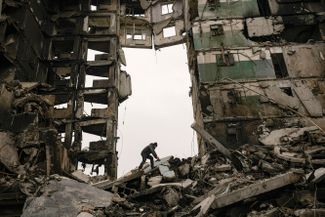 Жительница ищет вещи в руинах многоквартирного дома, разрушенного во время боев в Бородянке, Киевская область