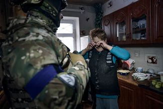 A policeman convinces a resident of Avdiivka to leave her house