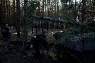 Украинские военные укрывают трофейный российский танк ветками, чтобы его не заметили в лесу