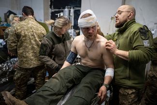 Украинские военные медики перевязывают раны солдату ВСУ