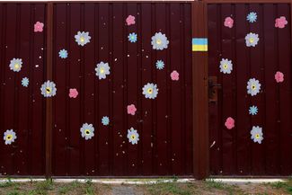 Цветы, нарисованные вокруг осколочных отверстий, образовавшихся в результате взрывов бомб в селе Мощун Киевской области. 26 августа 2023 года 