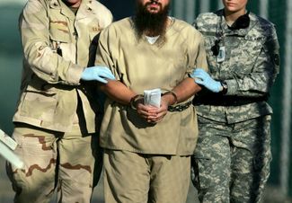 Гуантанамо в 2006 году: заключенного с документами в руках ведут в кандалах два американских солдата
