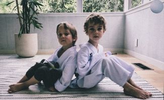 Lev, age 6, and Yan, age 4. Lev has been practicing Taekwondo for four years and Yan has been practicing for two. Lev already has five belts; most recently he got his green belt. Usually, the two boys take lessons at a studio, but because of the coronavirus, their training has been moved online.
