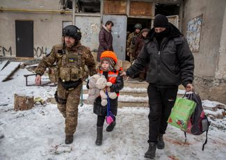 Ukrainian officers prepare a child wearing a ballistic vest for evacuation from Bakhmut. March 31, 2023.