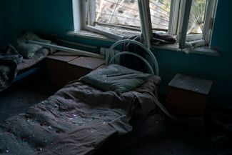 Кровать в психиатрической больнице, усыпанная осколками разбитого стекла, после удара российских войск по Краматорску