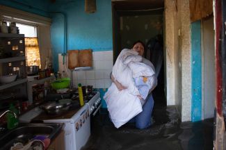 Жительница Херсона выносит постельное белье из своего затопленного дома. 7 июня 2023 года