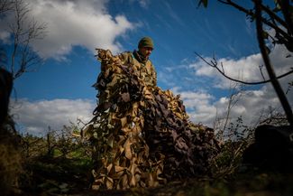 Украинский солдат маскирует свою позицию на линии фронта
