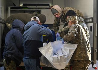 Украинские военнослужащие из проекта «На щите» переносят тело погибшего в машину, чтобы доставить его домой