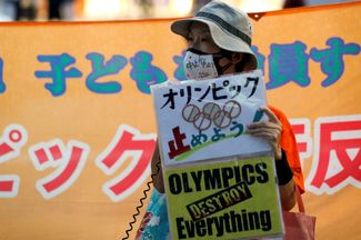 Участница акции против Игр с плакатом «Олимпийские игры уничтожат все», 8 июля 2021 года.