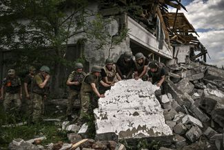 Украинские солдаты осматривают на окраине Лисичанска разрушенный склад, предположительно обстрелянный российскими войсками