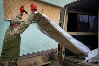 Украинский военный загружает тела убитых бойцов ВСУ в фургон
