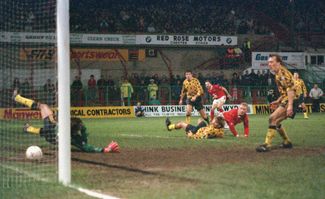 Нападающий «Рексема» Стив Уоткин (второй справа) забивает победный гол во время матча третьего раунда Кубка Англии между «Рексемом» и «Арсеналом». 4 января 1992 года